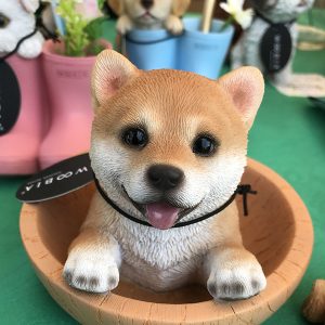 動物の置物| 木のボウルに入ったかわいい豆柴（芝犬）の置き物。舌を出してこちらを見上げています。