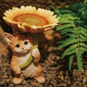 動物の置物｜花を傘のようにさしたかわいい茶トラ短足猫の置物。黒いつぶらな瞳でこちらを見上げる姿は庭の妖精のようです。